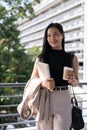 An attractive Asian businesswoman standing outdoors with a tablet and a takeaway coffee cup Royalty Free Stock Photo