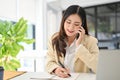 Attractive Asian businesswoman taking notes on her notebook while talking on the phone Royalty Free Stock Photo