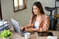 Attractive Asian businesswoman typing on keyboard, using laptop, woking at her desk Royalty Free Stock Photo