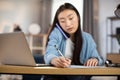 Asian woman talking on mobile and writing notes at workplace at home Royalty Free Stock Photo