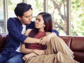 Attractive Asian couple spend time together , a woman sitting on couch making pout lips , leaning on her boyfriend  who smiling , Royalty Free Stock Photo