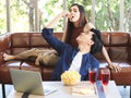 Attractive Asian couple spending good time at home , a man sitting on the floor with computer and popcorn on table and feeding