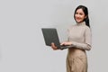 Attractive Asian female or businesswoman holding a laptop, standing against grey background Royalty Free Stock Photo