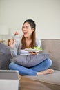 Attractive Asian female enjoys eating her healthy and organic salad in her living room Royalty Free Stock Photo