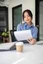 An attractive Asian female office worker is examining business documents at her desk Royalty Free Stock Photo