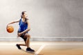 Attractive asian girl in blue sport uniform on basketball pivot moves on the basketball court