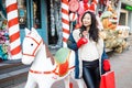 Attractive Asian girl with gift bag in her hands posing on a festive city street decorated for Christmas Royalty Free Stock Photo
