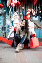 Attractive Asian girl with gift bag in her hands posing on a festive city street decorated for Christmas Royalty Free Stock Photo