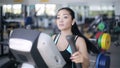 Attractive asian girl at the gym exercising on the xtrainer machine
