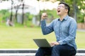 Attractive asian happy man gesture or raise hand excited screaming yes reading online good news or social network in laptop Royalty Free Stock Photo