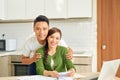 Attractive asian housewife having happy expression while calculating bills in kitchen