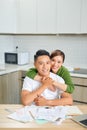 Attractive asian housewife having happy expression while calculating bills in kitchen