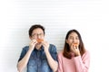 Attractive asian hungry couple eating pizza or fast food with smile and tasty facial expression on face with white wall background Royalty Free Stock Photo