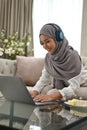 Attractive Asian Muslim woman using laptop computer in her living room Royalty Free Stock Photo