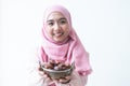 Attractive Asian 30s Muslim woman wearing traditional clothes with pink hijab headscarf, holding a bowl of dry dates fruit in Royalty Free Stock Photo