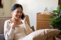 An attractive Asian woman enjoys talking with her friend on the phone while relaxing on a couch Royalty Free Stock Photo