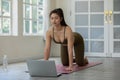 Attractive Asian woman looking laptop practice yoga Cat Cow pose online course at home to meditation comfortable and relax Royalty Free Stock Photo