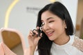 Attractive Asian woman looking at the mirror and using an eyelash curler to curl her eyelashes Royalty Free Stock Photo