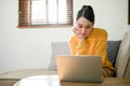 Attractive Asian woman remote working at home, focusing on her tasks on laptop Royalty Free Stock Photo