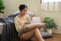 An attractive Asian woman is sitting beside her bed and enjoying her morning coffee in her bedroom Royalty Free Stock Photo