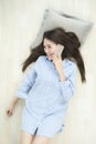 Asian woman speaking on the phone while laying on wood floor. Royalty Free Stock Photo