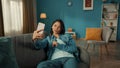 Attractive Asian woman takes a selfie on a smartphone, poses. A young woman is sitting on a sofa in the living room with Royalty Free Stock Photo