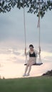 Attractive asian woman tourist happy playing swing under big tree in grass field. portrait smile cheerful female swinging alone in Royalty Free Stock Photo