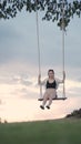 Attractive asian woman tourist happy playing swing under big tree in grass field. portrait smile cheerful female swinging alone in Royalty Free Stock Photo