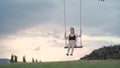 Attractive asian woman tourist happy playing swing under big tree in grass field. portrait smile cheerful female swinging alone in Royalty Free Stock Photo