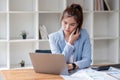 Attractive Asian woman using laptop in online meeting. Businesswoman using mobile phone talking with colleague sitting Royalty Free Stock Photo