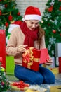 Attractive Asian woman wearing winter outfit and Santa`s hat unboxing gifts celebrating Christmas with joy. Decorated Christmas Royalty Free Stock Photo