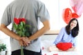 Attractive Asian woman being excited from her boyfriend surprise gift, man hiding beautiful red rose bouquet behind back, ready to Royalty Free Stock Photo