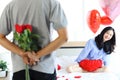 Attractive Asian woman being excited from her boyfriend surprise gift, man hiding beautiful red rose bouquet behind back, ready to Royalty Free Stock Photo