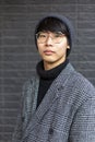 Attractive asian young man wearing coat, hat and glasses. Street fashion concept Royalty Free Stock Photo