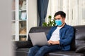 Attractive asian young man working working with laptop on couch, Work from home ideas Royalty Free Stock Photo