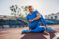 Attractive athlete young male stretching his leg on a running track in stadium, preparing for running and jogging. Caucasian man Royalty Free Stock Photo