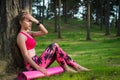 attractive athletic woman wearing smart watch is enjoying last rays of sun for the day after her workout in a forest.