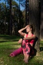 attractive athletic woman wearing smart watch is enjoying last rays of sun for the day after her workout in a forest.