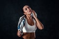 Attractive athletic young woman with perfect body wearing sportswear is posing with a towel against black background. Royalty Free Stock Photo