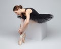 Attractive ballerina poses gracefully while sitting on a cube. photo shoot in the studio on a white background