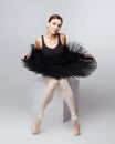 Attractive ballerina poses gracefully while sitting on a cube. photo shoot in the studio on a white background