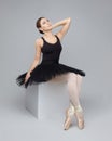 Attractive ballerina poses gracefully while sitting on a cube. photo shoot in the studio on a white background