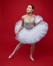 attractive ballerina poses gracefully in the studio on a red background