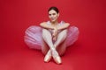 attractive ballerina poses in the studio on a red background