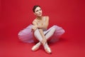 attractive ballerina poses in the studio on a red background