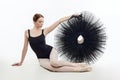 Attractive ballerina sits and holds a tutu in her hands. studio photo shoot on a white background