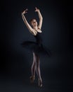 Attractive ballerina stands on her fingertips. photo shoot in the studio on a dark background