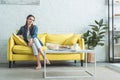 attractive barefoot girl sitting on sofa and smiling at camera Royalty Free Stock Photo