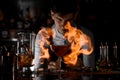 Attractive bartender watching on the fire around the cocktail glass