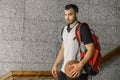 Attractive basketball player carries an orange ball and a red backpack, leaving the building where he lives Royalty Free Stock Photo